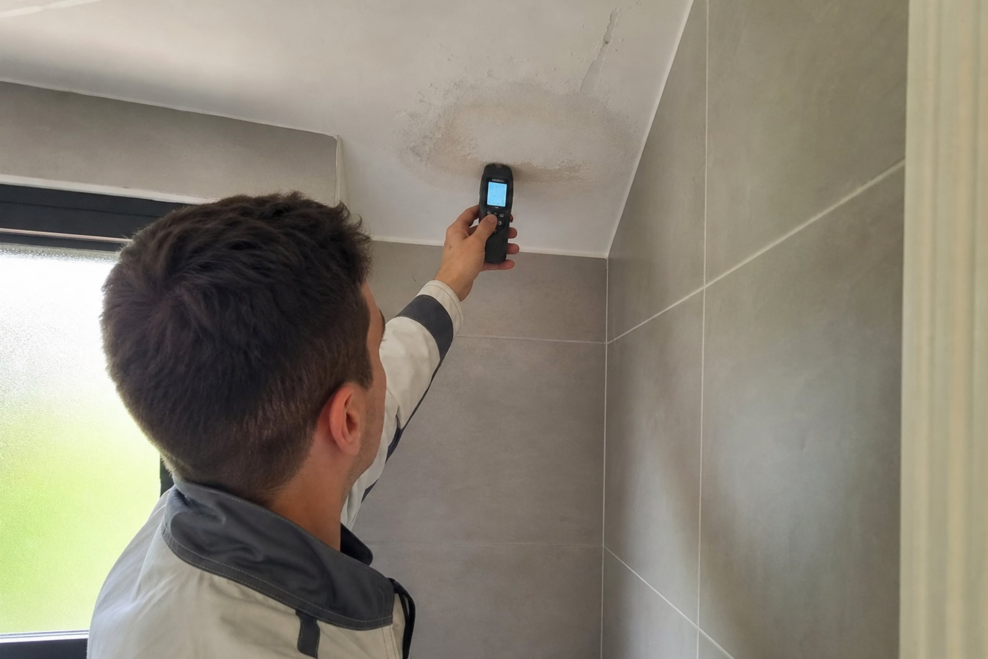 technicien mesure une tache d’humidité au plafond salledebain