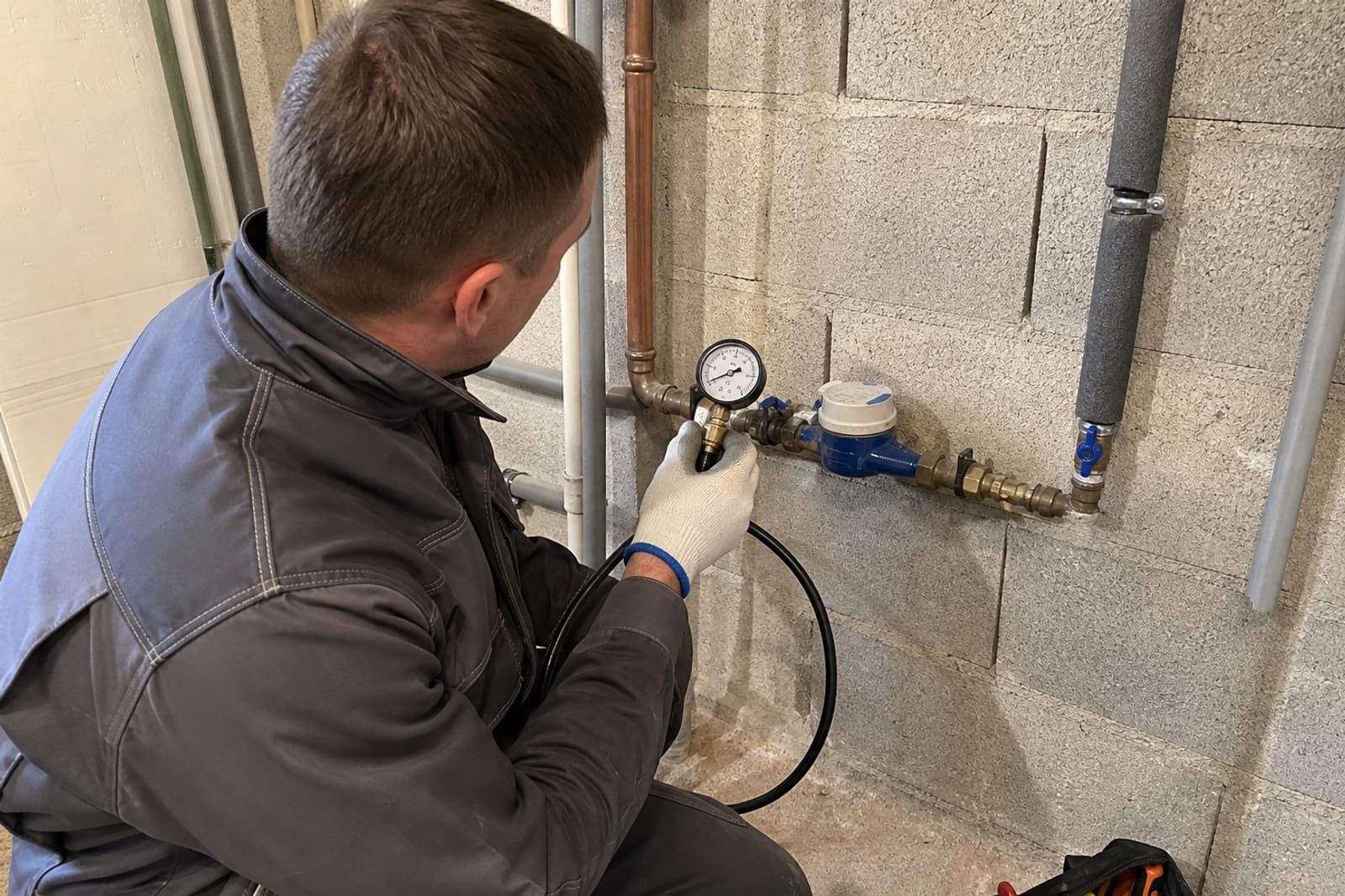 technicien lit manomètre sur réseau d’eau près compteur