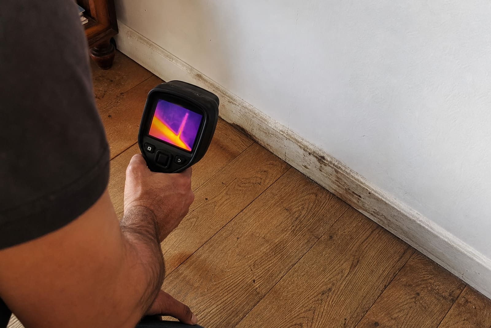 caméra thermique inspecte plinthe dans salon parquet